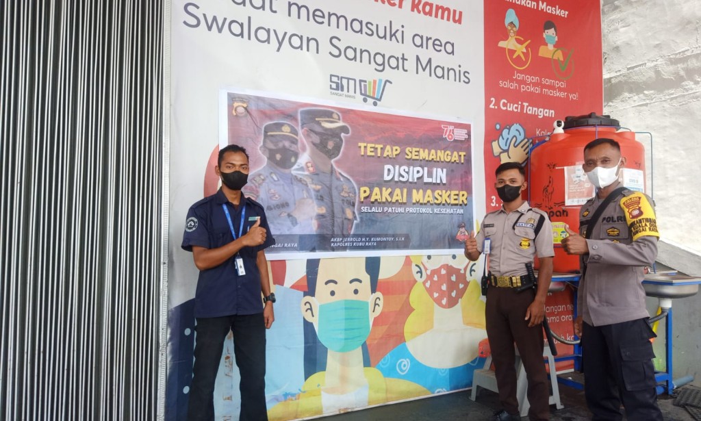 Ajak warga Displin Protokol Kesehatan, Bhabinkamtibmas Desa Kuala Dua Pasang Spanduk di Pusat Swalayan
